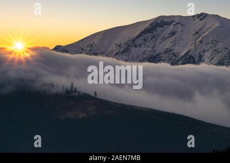 Alba sul terrapieno da nuvole traboccante sulle cime delle montagne Foto Stock