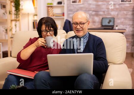 Nonna e nonno usando un computer portatile per chattare con i loro nipoti. Le persone anziane usando tecnologie moderne Foto Stock