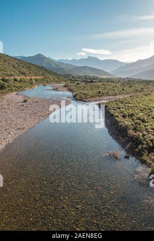 Le acque cristalline del fiume di fango vicino a Galeria in Corsica con la neve montagna ricoperte di Paglia Orba a distanza Foto Stock