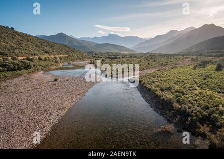 Le acque cristalline del fiume di fango vicino a Galeria in Corsica con la neve montagna ricoperte di Paglia Orba a distanza Foto Stock