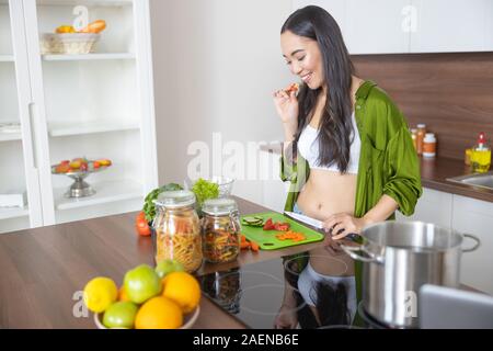 Cuocere sorridente che guarda il trito di verdure Foto Stock