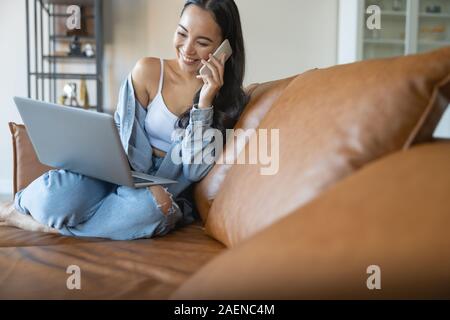 Ragazza ridere seduto su un divano in pelle Foto Stock