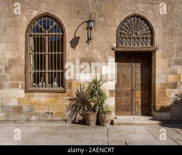 Facciata del vecchio abbandonato mattoni di pietra della parete arcuata con porta in legno e vetro con coperta in ferro battuto e la Lanterna, Il Cairo, Egitto Foto Stock