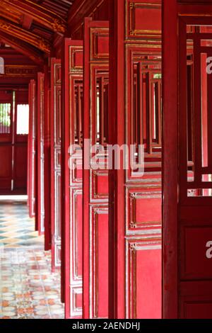 Un sacco di rosso le porte nel corridoio tra gli edifici in viola la città proibita (cittadella imperiale) in tinta, Vietnam Foto Stock