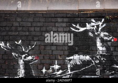 Un nuovo Banksy illustrazione in Birmingham Jewellery Quarter sembra essere stato soggetto ad atti vandalici giorni dopo che è apparso per la prima volta. Il dipinto raffigura due renne dipinta su un muro di mattoni che appaiono per tirare lungo un banco. Foto Stock