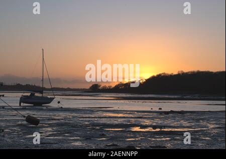 Tramonto a Dell Quay sailing club nelle vicinanze del Chichester. Sun appena oltre l'orizzonte impostazione in un tripudio di colori e la riflessione dell'acqua e sabbia. Foto Stock