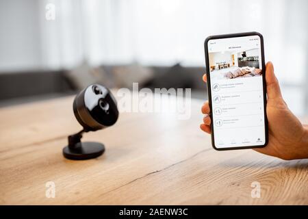 Close-up su uno smart phone con lanciato applicazione per la sicurezza e la telecamera IP al tavolo. Home video il concetto di sorveglianza Foto Stock