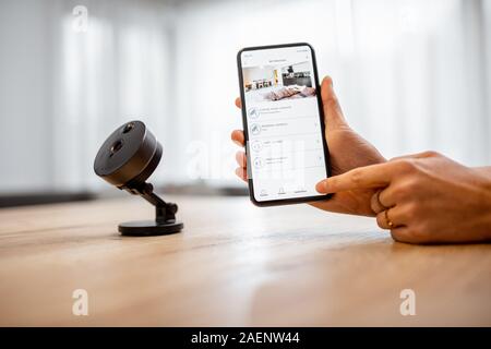 Close-up su uno smart phone con lanciato applicazione per la sicurezza e la telecamera IP al tavolo. Home video il concetto di sorveglianza Foto Stock