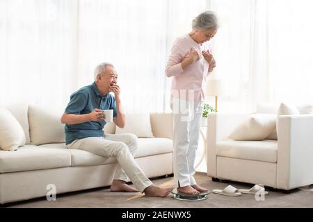 Senior moglie del peso di se stessa su una scala Foto Stock