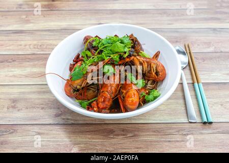 Chongqing Sichuan piccante peperoncino essiccato piccole aragoste, con bacchette & cucchiaio. Isolato di fotografia di cibo al ristorante cinese. Foto Stock