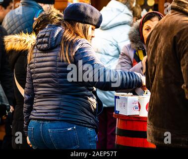 Le persone aventi il pranzo con il rumeno tradizionale cibo a Bucarest il mercatino di Natale. Bucarest, Romania, 2019. Foto Stock