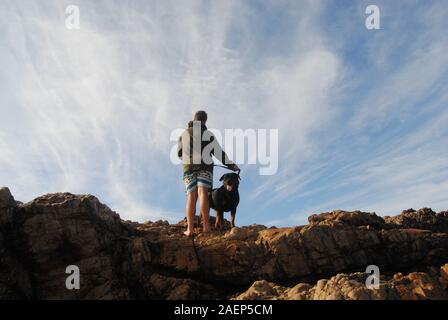 Happy dog con il proprietario sulla spiaggia rocciosa Foto Stock