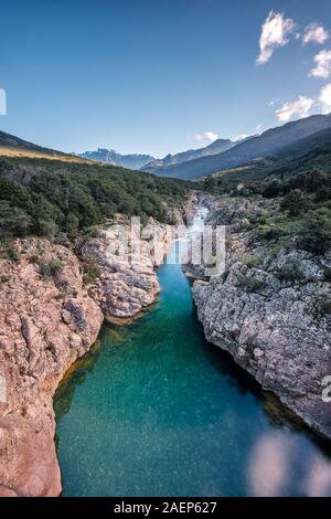 Le acque cristalline del fiume di fango vicino a Galeria in Corsica con la neve montagna ricoperte di Paglia Orba a distanza Foto Stock