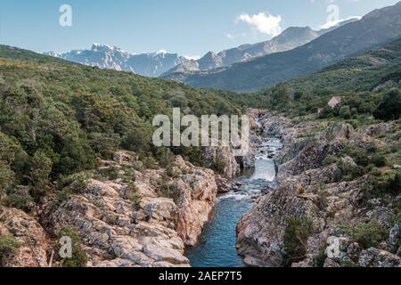 Le acque cristalline del fiume di fango vicino a Galeria in Corsica con la neve montagna ricoperte di Paglia Orba a distanza Foto Stock