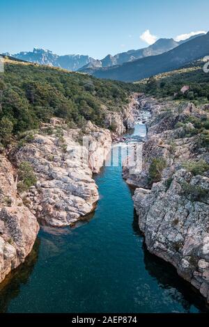 Le acque cristalline del fiume di fango vicino a Galeria in Corsica con la neve montagna ricoperte di Paglia Orba a distanza Foto Stock
