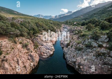 Le acque cristalline del fiume di fango vicino a Galeria in Corsica con la neve montagna ricoperte di Paglia Orba a distanza Foto Stock