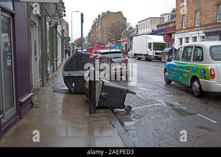 Edimburgo, Scozia, Regno Unito. Il 10 dicembre 2019. I forti venti che colpiscono il centro di Edimburgo attualmente 41 km/h SSW e raffiche di vento: 72 km/h con showery pioggia che si sente come grandine sulla pelle a causa della forza del vento. Mercatino di Natale e il castello chiuso, finestra soffiata fuori in negozio in Princes Street, rami all'Inverleith Park, cassonetti bruciato sul marciapiede in Raeburn Place e un medio anziana signora soffiata oltre in Princes Street. Foto Stock