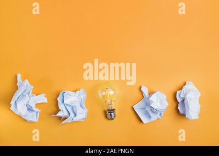 Idee concetti con lampadina e carta accartocciata sulla sfera di colore giallo brillante colore di sfondo Foto Stock