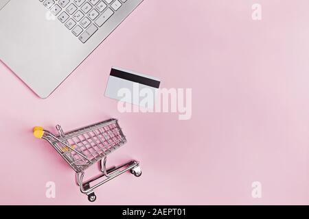Laptop, carte di credito e piccoli carrello della spesa , vista dall'alto. Foto Stock