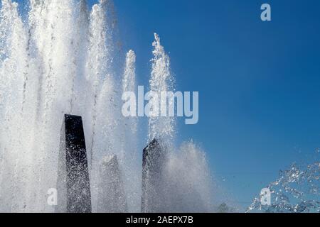 Getto d'acqua da una fontana verticale ritagliato contro un cielo blu. Foto Stock