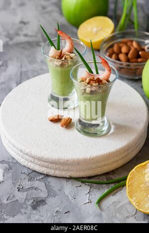 Avocado e mela verde mousse con gamberi e mandorle. Porzione antipasto per un buffet o un banchetto in un bicchiere. Foto Stock