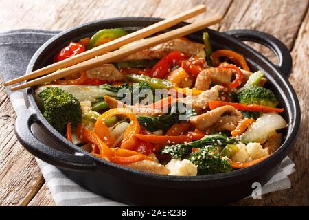 In stile asiatico di maiale fritto con broccoli, cavolo cinese, carote, peperoni, cavolfiore close-up in una padella sul tavolo orizzontale. Foto Stock