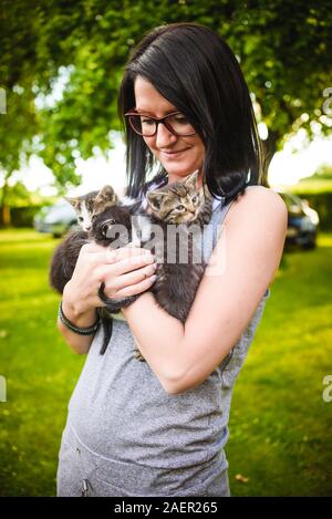 Giovane donna holding adorabili gattini in armi. Foto Stock