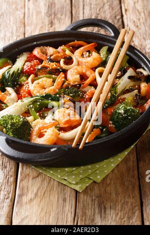 Stir-Gamberi fritti, calamari e cozze con verdure fresche di close-up in una padella sulla tavola verticale. Foto Stock