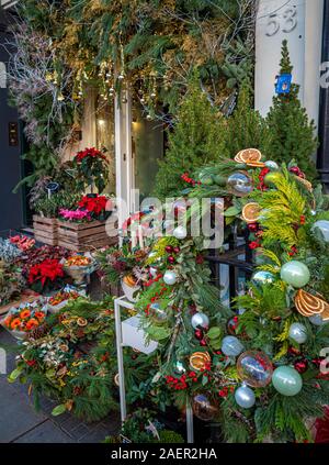 Natale corone di fiori e piante al di fuori di un fioraio a Belgravia, Londra, Regno Unito. Foto Stock