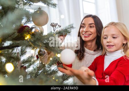 Famiglia sorridente raggiungendo per le decorazioni natalizie Foto Stock