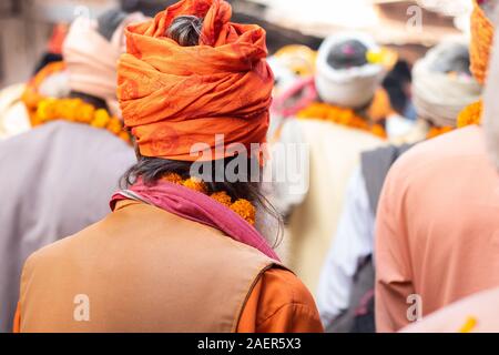 Sadhu indiano in folla andando per rally spirituale. Saggio indiano indossando vestiti arancioni e turbante e tenendo la ghirlanda di fiori traduzione parola: la sua "RAM' Foto Stock