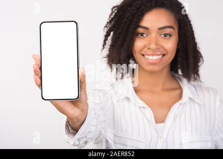 Nero donna millenaria che mostra vuota dello schermo del telefono Foto Stock
