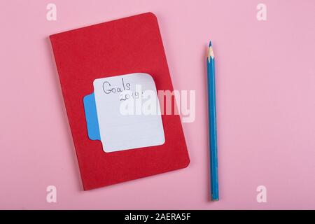 Promemoria e concezione di business - Obiettivi 2019 testo con stick nota carta, il blocco note e matita su sfondo rosa Foto Stock