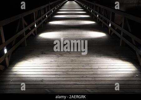 Ponte di legno illuminato dalla circolare bianco luci di notte, in prospettiva Foto Stock