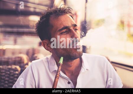 Inquadratura ravvicinata di un elegante adulto ragazzo di fumare narghilè indoor di un cafe Foto Stock