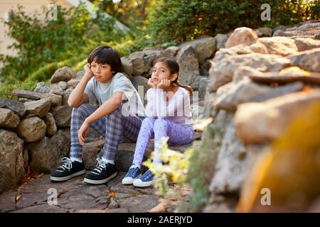 Infelice fratello e sorella seduta accanto a ciascun altro su un gradino di pietra. Foto Stock