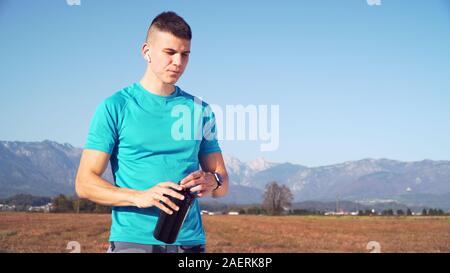 Montare il giovane uomo preparazione protein shake e beve con montagne retro Foto Stock