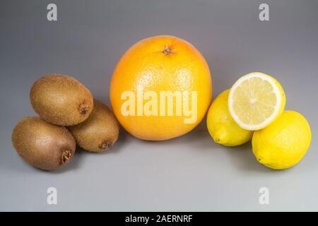 Frutti invernali, pompelmo, kiwi e limoni su sfondo di legno Foto Stock