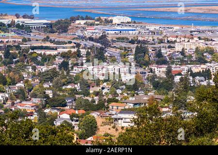 Vista aerea di San Carlos in Silicon Valley ; zone residenziali con case costruite sulle colline in primo piano; le aree industriali e il litorale di Sa Foto Stock