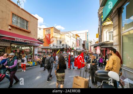 Turchi locali shopping il grande Eminonu mercato outdoor bazaar come essi a piedi vicino a battenti bandiera turca ad Istanbul in Turchia Foto Stock