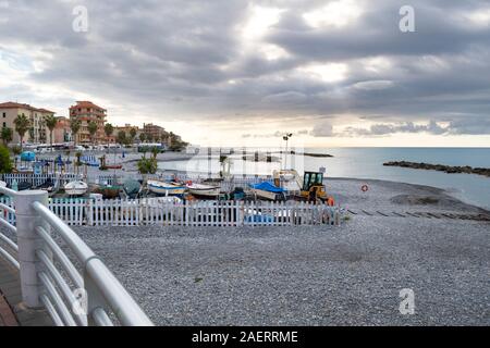 Linea di imbarcazioni la costa rocciosa e la spiaggia la mattina presto nella cittadina balneare di Ventimiglia, Italia, sulla Riviera Italiana. Foto Stock