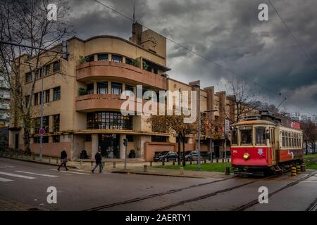 Red tram storico street auto passando da un originale edificio Art Deco in Porto Portogallo Foto Stock