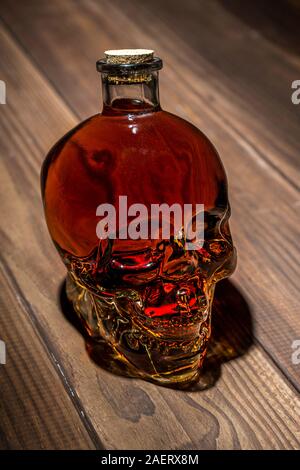 Bottiglia a forma di teschio con alcool. Il concetto di danno da alcol. L' alcolismo. Foto Stock