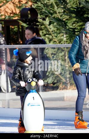 La ragazza impara a pattinare sul ghiaccio con un dummy avente fun focalizzata sulla madre Foto Stock