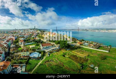 Panoramica aerea del 25 aprile ponte sopra il fiume Targus tra Lisbona e Almada con un gigantesco Gesù Cristo statua e il castello di Almada Foto Stock