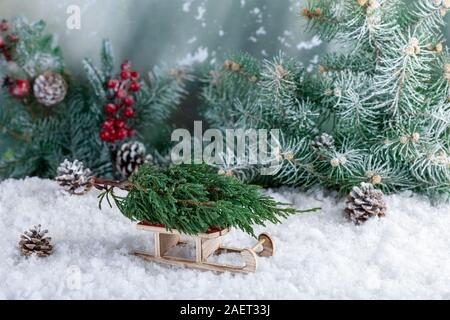 Composizione decorativa di decorazioni di Natale fatto di piccoli abete su Babbo Natale con la slitta. Abstract con sfondo verde rami di abete, coni e w Foto Stock