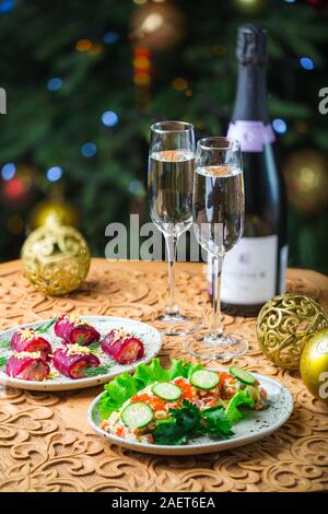 Concetto di Natale . Tabella coperta con cibo e nuovi anni paraphernalia sorge in una sala decorata per il nuovo anno Foto Stock