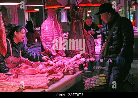 I clienti acquistano la carne di maiale intorno uno stand presso il locale mercato alimentare di Tianjin, Cina, 16 novembre 2019. Il prezzo della carne di maiale continua andando giù come governo o Foto Stock