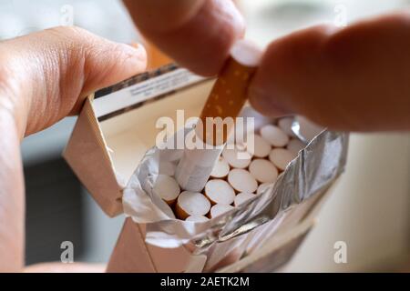 Stretta di mano scegli una sigaretta dal cartone confezione di imballaggio Foto Stock