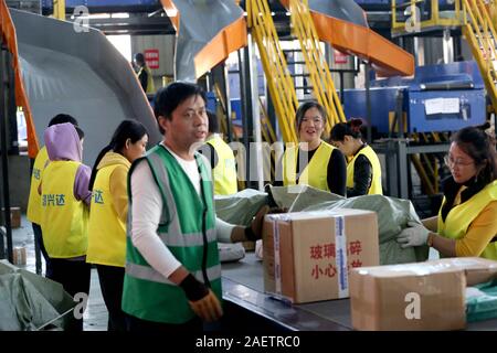 Lavoratori a EMS (Express Mail Service) centro logistico di riordinare i pacchi come doppio 11 picchi di erogazione in Huai'an City, est della Cina di provincia dello Jiangsu Foto Stock